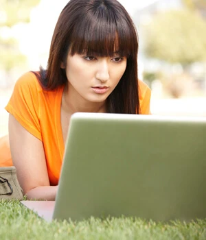 woman on laptop in the grass.