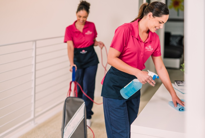 Molly Maid professionals cleaning a hallway area in a home.