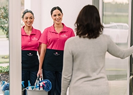 Pair of female Molly Maid employees greeting customer at their door.