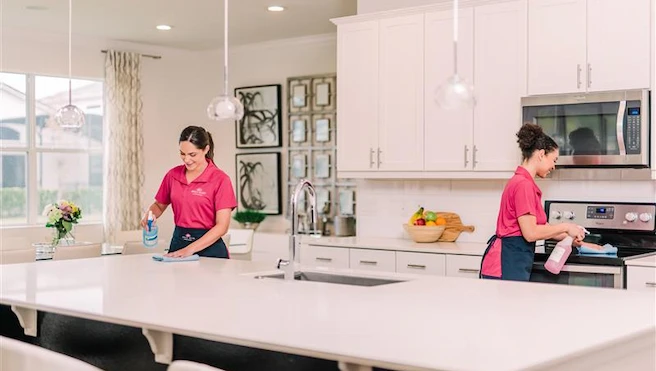 Pair of Molly Maid professionals cleaning kitchen.