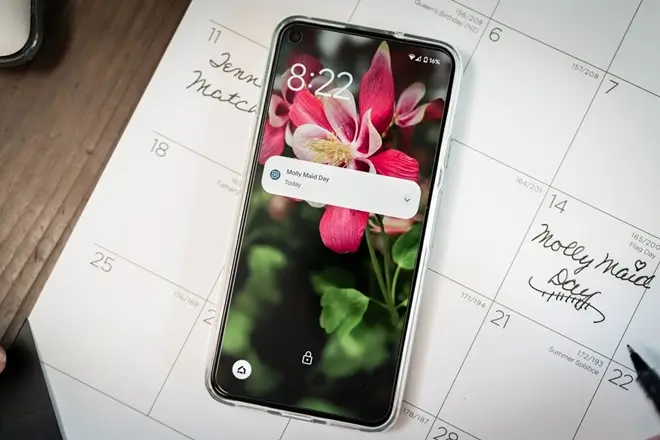 Customer cell phone on top of calendar showing a Molly Maid cleaning appointment. 