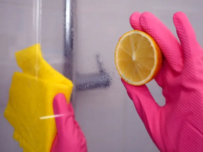 Eco-friendly cleaning of shower screen using natural lemon juice to remove limescale