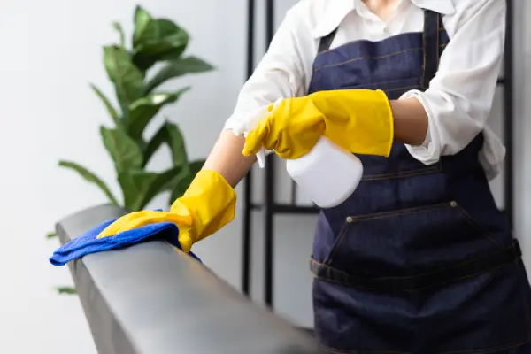 A cleaning professional disinfecting a metal railing.