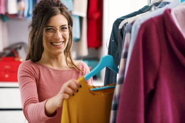 Woman hanging up clothes in her bedroom closet.