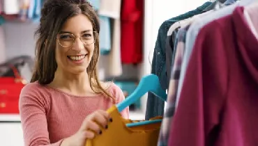 Woman hanging up clothes in her bedroom closet.