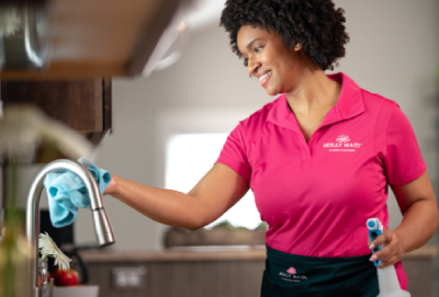 A Molly Maid professional wipes down a kitchen faucet during a post-party cleanup service.