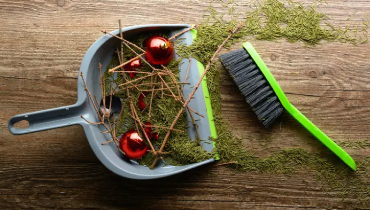 Sweeping up leftover pine needles and ornaments for post-holiday cleanup.